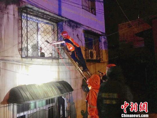 消防指战员对居民楼窗户实施破拆，利用拉梯搭建救援通道。宜昌消防供图