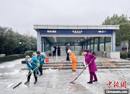 地鐵工作人員和環(huán)衛(wèi)工作人一起掃雪除冰。武漢地鐵集團供圖