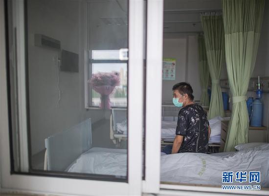 6月17日，胡定江在病房等待出院，窗台的鲜花是他准备在出院时送给医护人员的。新华社记者 肖艺九 摄