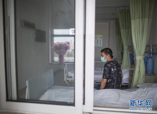 6月17日,胡定江在病房等待出院,窗台的鲜花是他准备在出院时送给医护人员的。新华社记者 肖艺九 摄