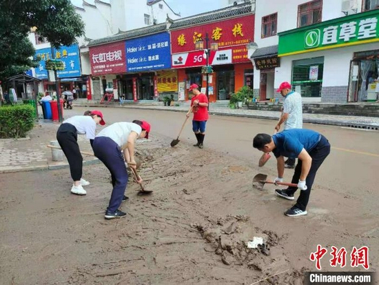 三斗坪镇干部群众正在清理街道上的淤泥。　三斗坪镇政府供图