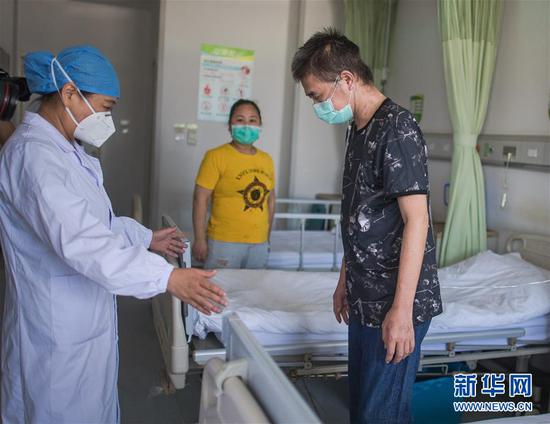 6月17日，医生朱琦在病房检查胡定江的恢复情况。新华社记者 肖艺九 摄