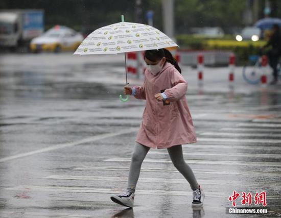 资料图:市民冒雨出行。 于海洋 摄