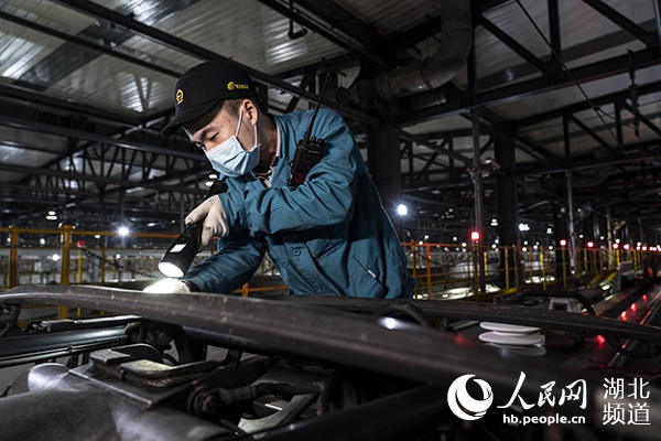 武汉动车段运用车间检修班工长程满和同事们正在对今日始发的动车做最后检查。(邹政 摄)