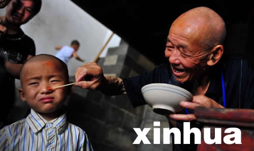2012年6月19日,湖北省茅坪镇的一位老人在给孩子涂抹雄黄酒。用雄黄酒涂抹于小孩额头或画“王”字,一借雄黄以驱毒防虫子叮咬,二借猛虎(“王”似虎的额纹,又虎为兽中之王,因以代虎)以镇邪。寓意让小孩一长成人。