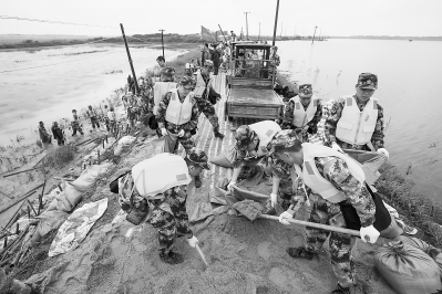 部队官兵在堤坝上紧急装运填埋沙袋抢险。记者胡九思 通讯员 王安 摄