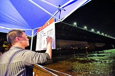 7月5日午夜1点17分,在武昌江堤中华路街防汛值守点,防汛人员在责任牌上登记到岗人员。记者詹松 摄