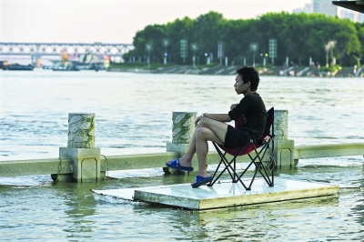 昨日下午，龙王庙江滩亲水平台仍淹没在水中，一位市民用门做成“漂流板”，坐在上面赏着江景，怡然自得。记者胡冬冬 摄（实习生 李蓓）