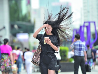 昨日江城迎来降温，大风骤起。国广楼前，一位女士迎风走过，长发飞扬
。记者胡冬冬 摄