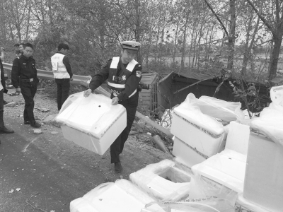 民警正在从侧翻的货车上搬运用泡沫箱装载的河豚   省高警荆州大队提供