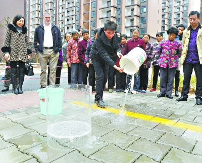 现场一位居民将一大桶水泼洒在小区路面上，2秒钟，水全部被“喝干”，路面变得干爽如初。记者刘斌 摄