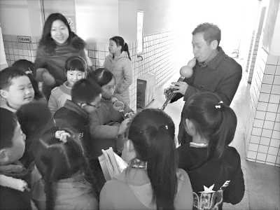 昨日课间，钢花小学校长蔡伦涛在办公室外吹起葫芦丝，引来学生们“围观”      见习记者邓小龙 摄