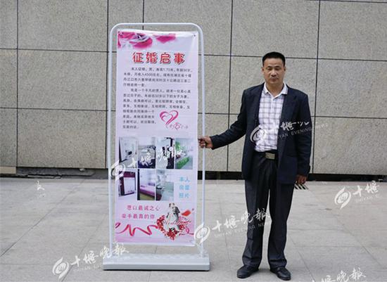 王先生站在街头举牌征婚。