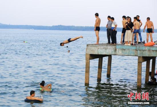 7月25日，武汉东湖凌波门露天泳池内，一位市民从高台上跃入湖中。当日，武汉中心气象台发布高温红色预警。武汉、十堰、襄阳等9个地市高温突破40℃。中新社记者 张畅 摄