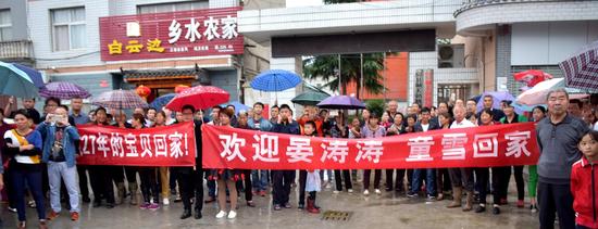 村民询讯赶到社区居委会举欢迎横幅迎接被拐27年的涛涛、小雪。新华社发(魏世银摄)