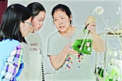 实验室内,中科院武汉水生所胡春香研究员查看学生韩迎春和李琪培养的荒漠藻的长势,并给出指导