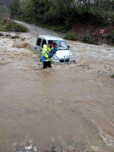 图为民警跳入湍急的河流中，抢救被困人员及车辆。