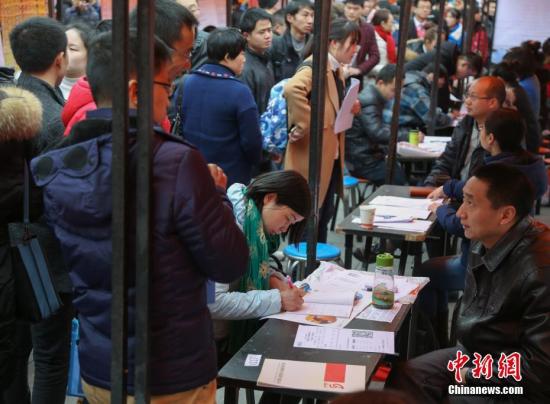 资料图:在武汉市纳杰人才市场招聘会上,挤满了前来应聘的求职者。中新社记者 张畅 摄