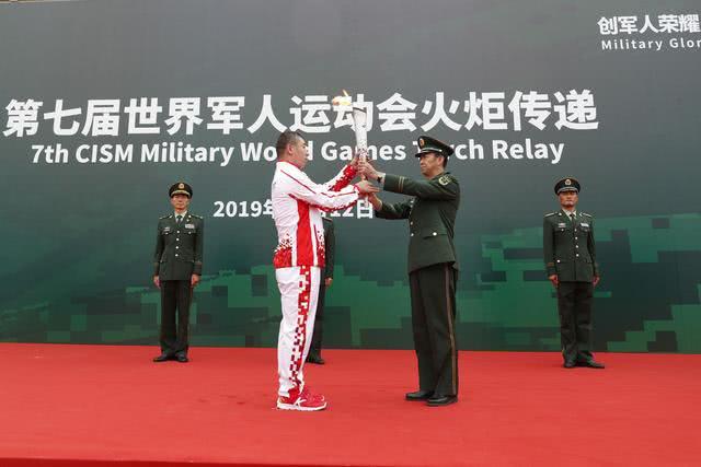 10月12日，第七届世界军人运动会军营火炬传递活动最后一站武警猎鹰突击队站举行。图为传递单位领导（前右）将火炬交给第一名火炬手朱忠华（前左）。新华社发