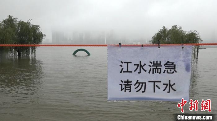 工作人员在江边拉起红色警戒线，提醒市民不要下水 张芹 摄