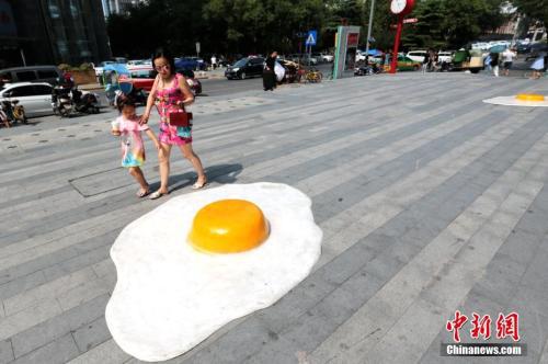7月30日，数个巨型“煎蛋”模型“摊”在西安一商场门前，吸引过往行人注目。连日来，西安持续高温天气，最高气温超过40℃。中新社记者 张远 摄