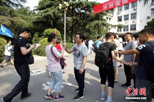 资料图：2018年6月7日，山东省实验中学考点，考生们陆续走进考场，老师为考生们加油鼓劲。中新社记者 王占波 摄