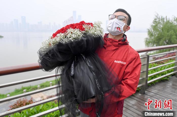 王育林手捧鲜花等待女友前来。 杨华峰 摄
