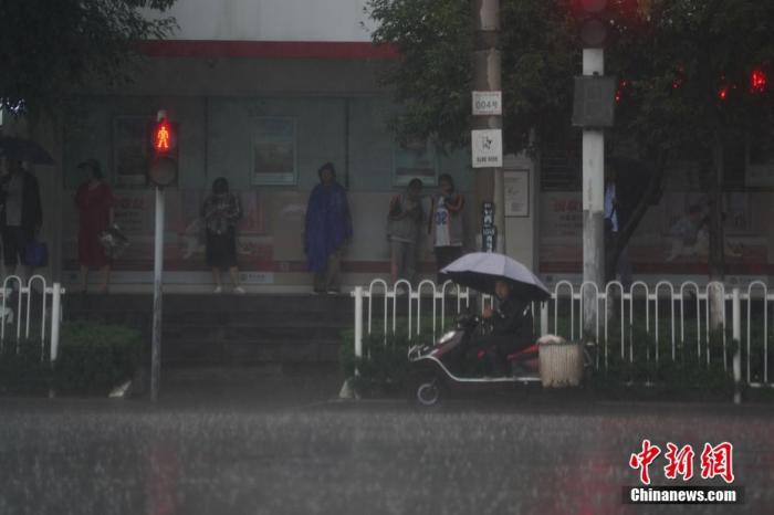6月18日下午，云南省昆明市突降暴雨，市民在街边避雨。 中新社记者 刘冉阳 摄