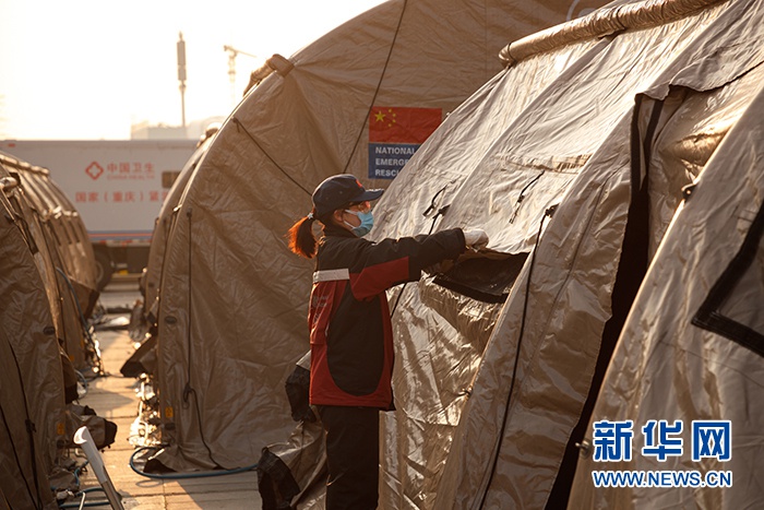 图为武汉客厅方舱医院工作人员搭建医用帐篷。新华网发 董宏祥摄