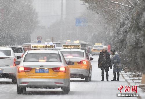 12月7日，一夜的降雪令新疆喀什市披上白裝，當(dāng)?shù)刈畹蜌鉁亟抵亮阆?攝氏度。圖為民眾在路邊等候出租車趕去上班。中新社記者 劉新 攝