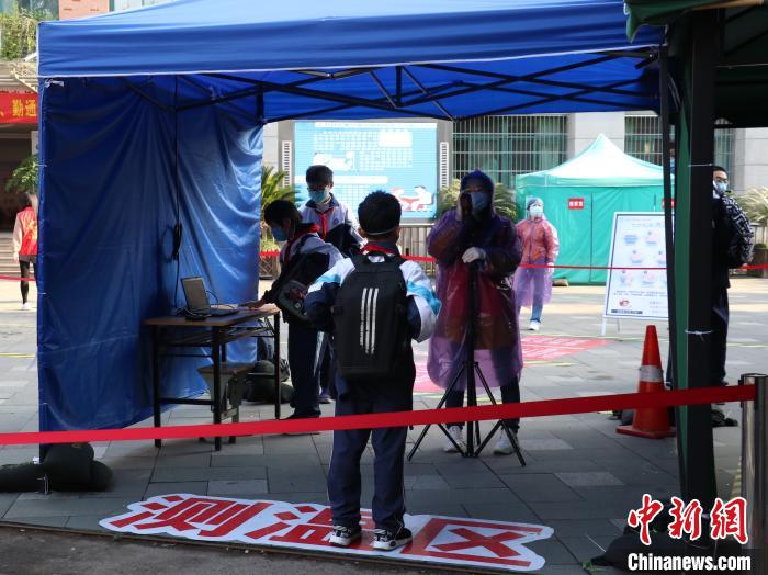 学生进校前测量体温。 童笑雨 摄