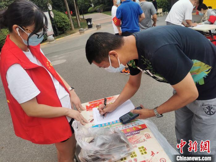 圖為周金麗（左）在小區(qū)卡口協(xié)助登記居民信息 受訪者供圖