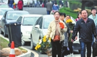 市民手拿鲜花前去祭扫 记者肖僖 摄