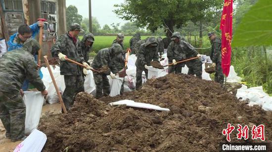 防汛人员挥锹铲土,装填沙袋,对堤坝进行加高加固。 周璇 摄