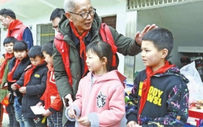 78岁的游启发老先生亲自将助学金交到受助孩子手里