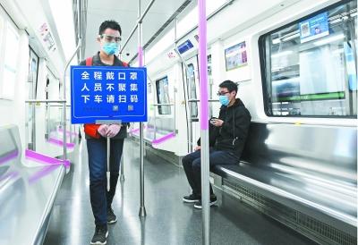 在開往光谷的地鐵上，工作人員舉著“全程戴口罩、人員不聚集、下車請(qǐng)掃碼”的提示牌巡查長(zhǎng)江日?qǐng)?bào)記者高勇 攝