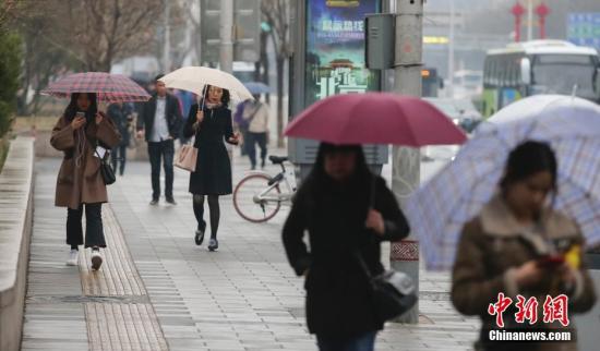 资料图：民众在雨中出行。中新社记者 贾天勇 摄