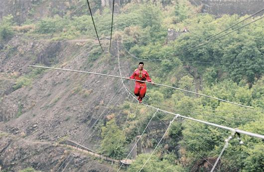 图为：昨日，第七届黄石铁山槐花旅游节迎来重头戏，新疆达瓦孜（高空走钢丝）第七代传人赛买提·艾散，用时24分20秒跨越“亚洲第一天坑”。 通讯员周国强摄