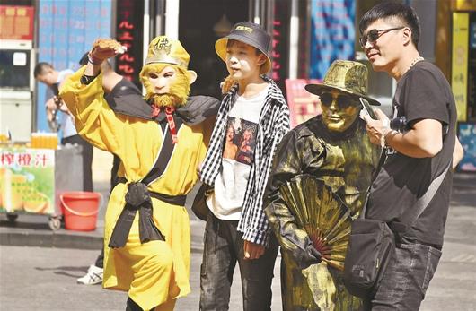 圖為：前日上午，“孫悟空”和“銅人”在戶部巷門口與游客合影