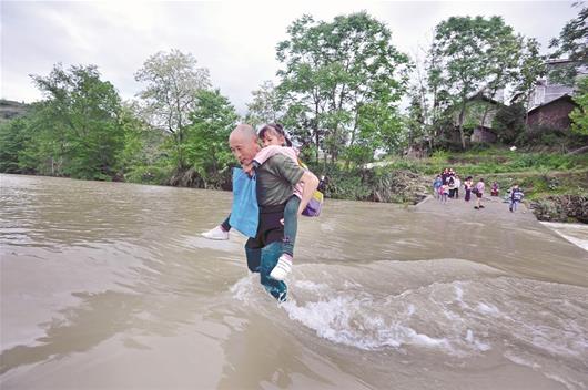 图为:侯长辉在背孩子过河通讯员彭涛摄
