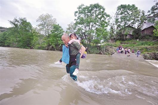 图为：侯长辉在背孩子过河通讯员彭涛摄