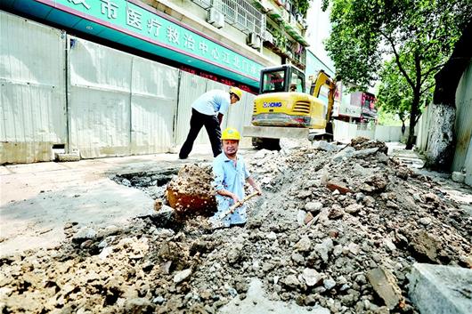 图为在江汉北路施工现场，工人师傅人工开挖管线