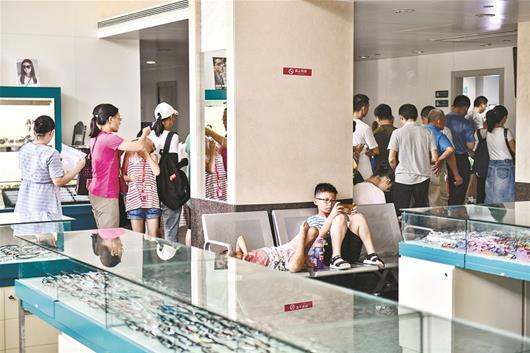 图为眼科诊室外,不少孩子戴着眼镜玩手机