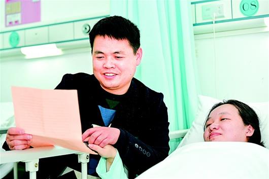 图为:产妇胡稳在ICU病房内听丈夫给她念信