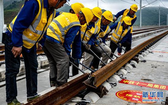 4月26日，中铁十一局建设者在安九高铁温碧岭特大桥进行铺轨作业。新华社记者 杜华举 摄