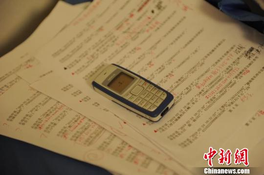 警方查获的用于诈骗的手机及“剧本”。夷陵警方 供图