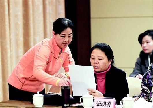 图为:1月23日,妇女联合会界别分组讨论前,委员付鄂玲(左)向其他委员介绍自己的提案。 (湖北日报全媒记者 张朋 摄)