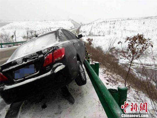 丹江口境内，雨雪导致路面湿滑，一辆轿车“骑”上护栏　程军　摄