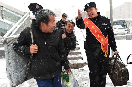 1月3日，湖北省襄阳市，襄阳车站派出所与车站职工组成的青年志愿者服务小分队帮助赶车的旅客。当日，湖北省多地迎来新年的第一场雪。贺瑞明/摄