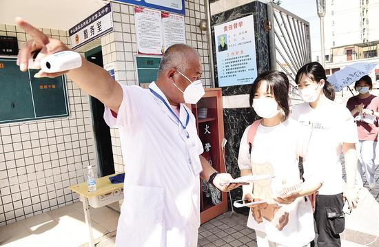 六月六日下午,沙市五中高考考点的工作人员对提前熟悉考点、查看考场的考生严格进行体温检测,并提供周到的服务保障工作。(通讯员 潘路 摄)